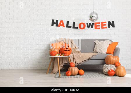 Interno di una camera elegante con divano, zucche e ballo da discoteca decorato per la festa di Halloween Foto Stock