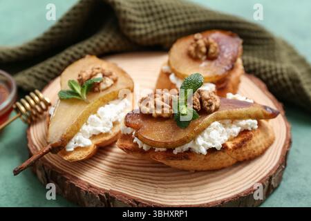 Tavola di legno di bruschetta di pera con ricotta e noci su sfondo verde, primo piano Foto Stock