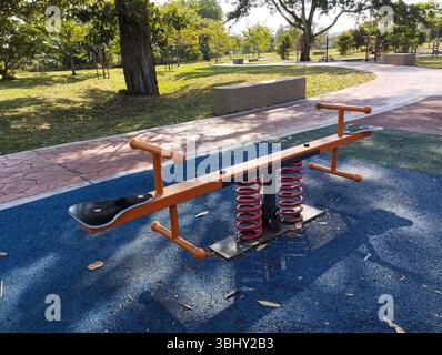 Colorato Seesaw in un Sunny Park Playground con alberi e sentieri Foto Stock