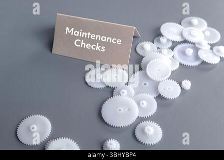 Controlli di manutenzione con ingranaggi assortiti in plastica bianca su sfondo grigio Foto Stock