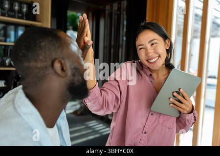 Felice coppia multietnica che utilizza un notebook, acquista online con le vendite, gioca insieme Foto Stock