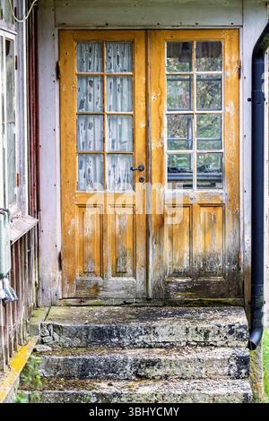 Porta di legno con finestre su un vecchio cottage abbandonato Foto Stock