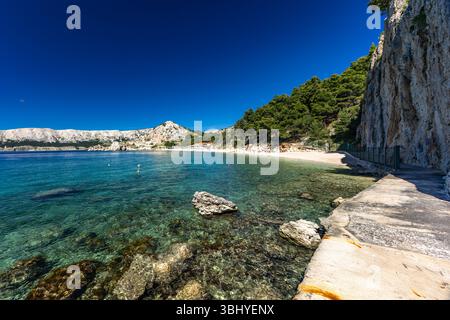Spiaggia di Jablanova sull'isola DI KRK in Croazia, sentiero blu che conduce a una spiaggia di ciottoli vuota, natura selvaggia e lussureggiante vegetazione mediterranea, panorama Foto Stock