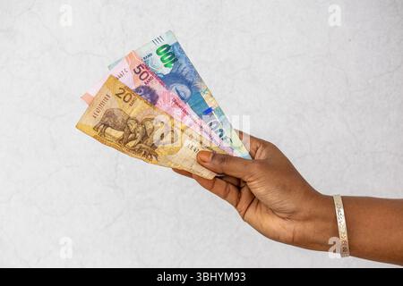 Mano femminile che tiene le banconote del Rand sudafricano R20 R50 R100. Concetto finanziario del denaro del Sudafrica. Foto Stock