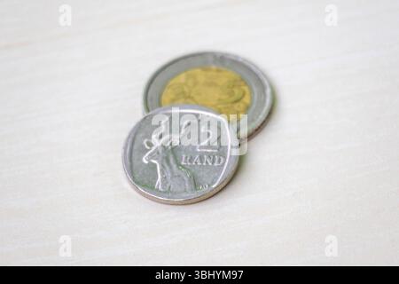 Due monete sudafricane Rand e 5 Rand su una superficie di legno chiaro. Foto Stock