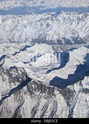 Una prospettiva aerea rivela una scena mozzafiato di aspre montagne innevate, con vette taglienti e profonde valli che creano un natu maestoso Foto Stock