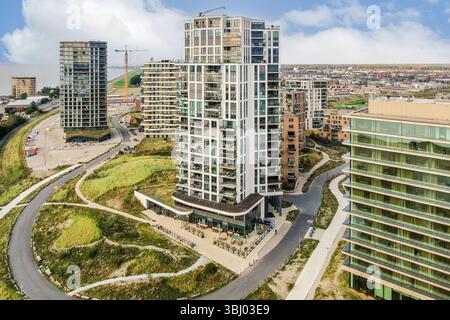 Una vista panoramica di un condominio contemporaneo circondato dal verde e dall'animato skyline cittadino sullo sfondo. Ideale per l'architettura urbana Foto Stock