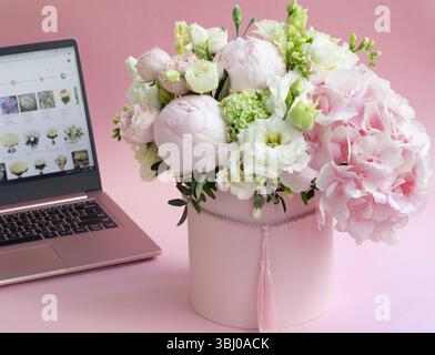 bouquet di fiori in una scatola da primo piano, sullo sfondo di un laptop aperto Foto Stock