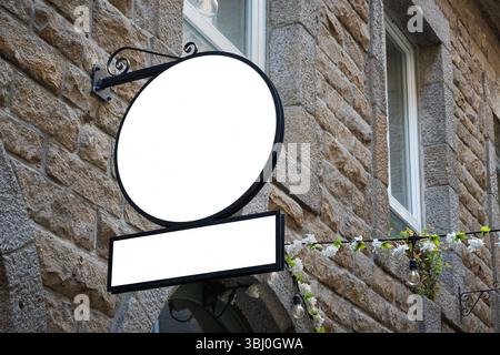 Mockup di insegne vuote su un muro di un edificio in pietra con pannelli rotondi e rettangolari. Ideale per il branding, la presentazione del logo o il design di vetrine. Foto Stock
