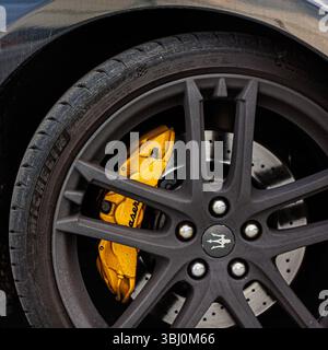 Kiev, Ucraina - 12 giugno 2025: Ruota Maserati con raggi neri opachi, una pinza freno gialla di primo piano Foto Stock