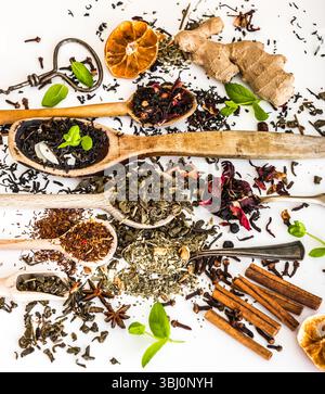 Tipi di tè viriosi in cucchiai di legno su un tavolo bianco Foto Stock