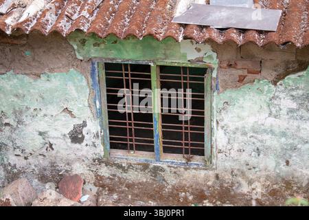 Vecchia casa a Munnar, India, vecchie griglie rustiche alle finestre, facciata con pareti di colore verde spezzato, mattoni e edifici in pietra Foto Stock