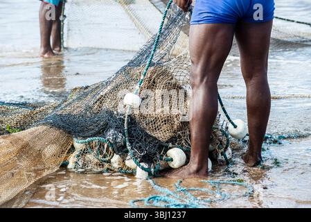 Mezzo corpo di pescatori non identificati che raccolgono la rete da pesca dopo la cattura del pesce. Pesce, pesca come hobby. Brasile Foto Stock