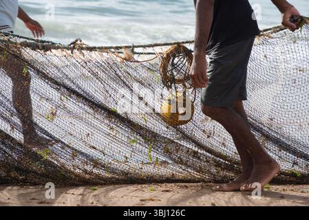 Mezzo corpo di pescatori non identificati che raccolgono la rete da pesca dopo la cattura del pesce. Pesce, pesca come hobby. Brasile Foto Stock
