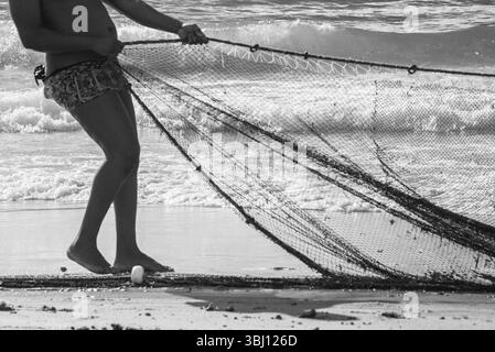 Mezzo corpo di un pescatore non identificato che tira una rete da pesca. specialità di pesce, hobby. Brasile Foto Stock