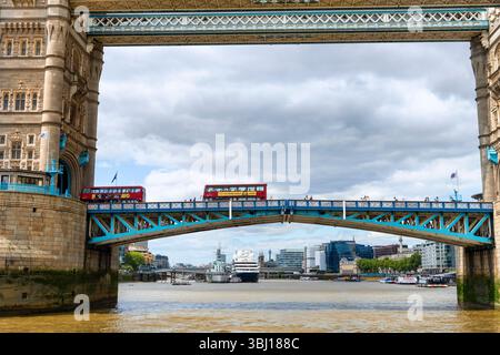Londra, Inghilterra, Regno Unito - 4 maggio 2025: L'iconico Tower Bridge e un autobus rosso a due piani che attraversa il Tamigi nella City di Londra, Regno Unito. Foto Stock
