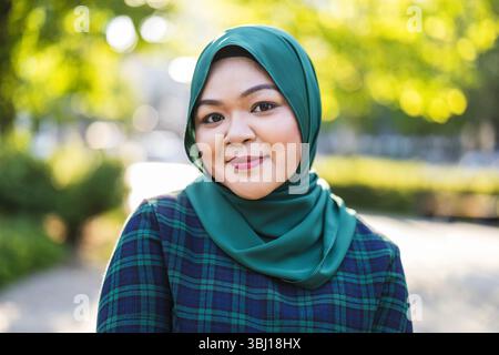 Ritratto di donna musulmana asiatica che indossa hijab sorridente alla macchina fotografica Foto Stock