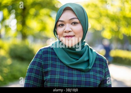 Ritratto di donna musulmana asiatica che indossa hijab sorridente alla macchina fotografica Foto Stock