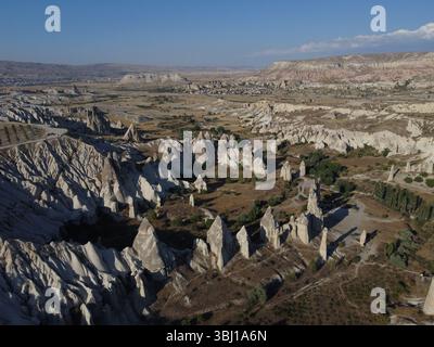 Uno splendido drone che sorvola la Love Valley in Cappadocia, mostrando le sue iconiche formazioni rocciose, il paesaggio surreale e le tonalità calde sotto un cielo limpido. Foto Stock