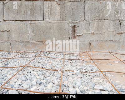 Immagine di un rinforzo in rete metallica su ghiaia, preparato per il versamento di calcestruzzo per costruire un robusto parcheggio accanto a una casa. Perfetto per la costruzione e. Foto Stock