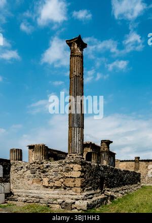 Un'antica colonna si erge su un cielo blu, con resti di altre strutture visibili sullo sfondo. Foto Stock
