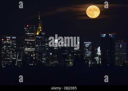 La luna piena, conosciuta come la luna delle fragole a giugno, passa sopra lo skyline bancario di Francoforte, Francoforte sul meno, Assia, Germania, Europa Foto Stock