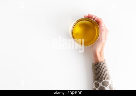 Una mano femminile che regge una tazza di tè su sfondo bianco con spazio per le copie. Foto Stock
