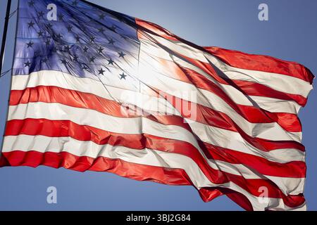 Spettacolare bandiera americana retroilluminata che ondeggia nel vento. Foto Stock