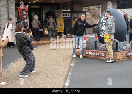 Fila di persone in attesa di farsi fotografare di fronte a un gigantesco uovo nero nella stazione di Owakudani di fronte al Museo Geo di Hakone in Giappone Foto Stock