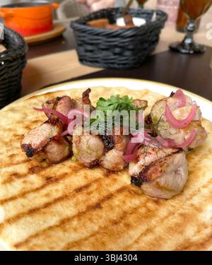 Pezzi di carne alla griglia con cipolle sottaceto su pancake, pita. Cucina tradizionale asiatica. Cibo e prodotti. Foto Stock