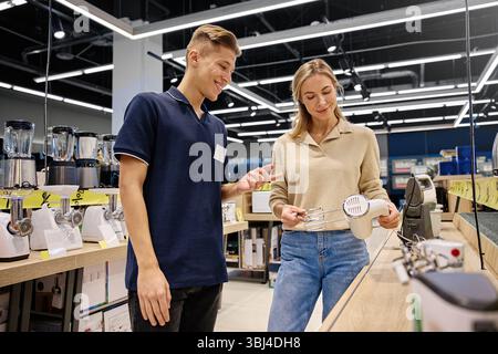 Uno scambio caldo e amichevole avviene tra un addetto alle vendite e un cliente in un moderno negozio al dettaglio, che mostra brillantemente il segno distintivo di ecc Foto Stock
