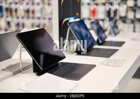 La vetrina presenta tablet eleganti e moderni abbinati a tastiere eleganti, splendidamente esposti in un negozio invitante per gli appassionati di tecnologia e i gadget Foto Stock