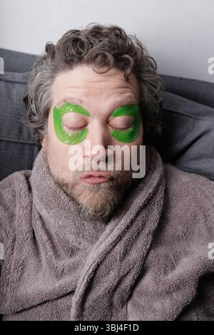 uomo sui quarant'anni con barba e tamponi idratanti sugli occhi Foto Stock