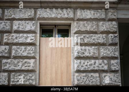Pannelli di legno che coprono la parte inferiore della finestra sulla facciata di un edificio in pietra Foto Stock
