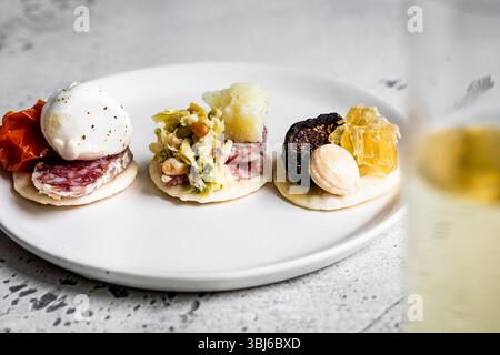 Un assortimento di antipasti gourmet su un piatto bianco, con vari condimenti sui cracker. Foto Stock