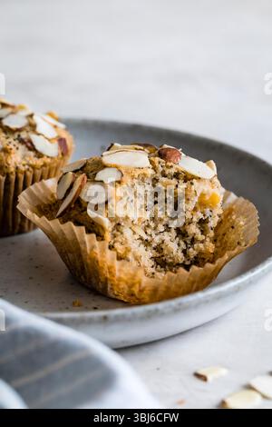 Primo piano di un muffin alle mandorle parzialmente mangiato su un piatto. Foto Stock