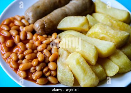 Londra, Regno Unito, 13 giugno 2025, salsicce di maiale britanniche preferite con patatine e fagioli al forno in salsa di pomodoro Foto Stock