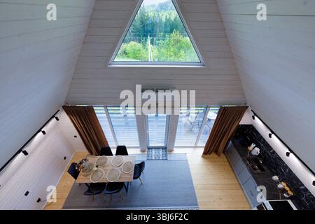 Ampia vista dal livello superiore di un elegante cabina con telaio A che presenta un'elegante zona pranzo, un'elegante cucina e uno splendido paesaggio naturale oltre le sue dimensioni Foto Stock