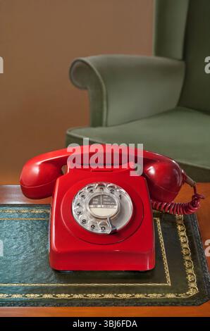 TELEFONO QUADRANTE ROTANTE stile anni '1970 rosso vecchio stile retrò stile britannico classico ufficio casa GPO BT telefono rosso scrivania antica e sedia vintage Foto Stock