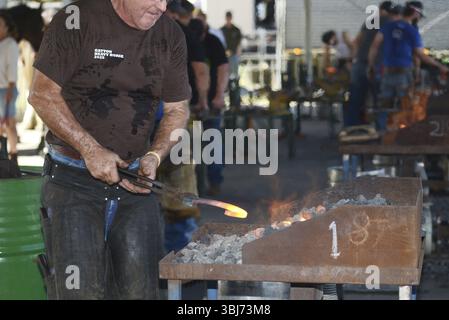GATTON, AUSTRALIA, 2 MAGGIO 2025: Un allevatore non identificato estrae un nuovo ferro di cavallo dalla fucina mentre è ancora rosso caldo Foto Stock