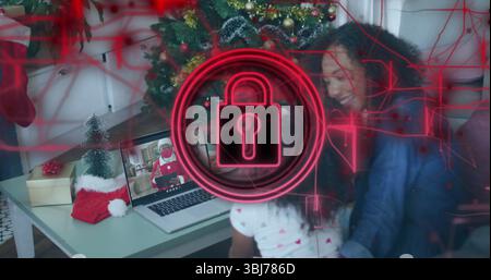 Madre e figlia guardano Babbo Natale su un laptop nel soggiorno, con calze, regali e alberi Foto Stock