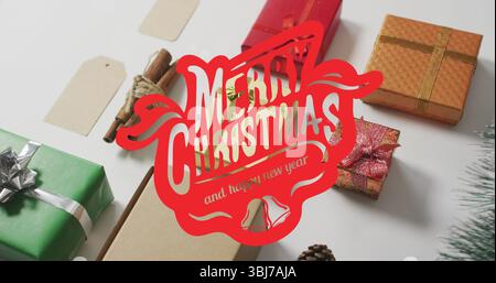 Esposizione di confezioni regalo con bastoncini di cannella e pinecone con un messaggio di saluto rosso su un piano bianco Foto Stock