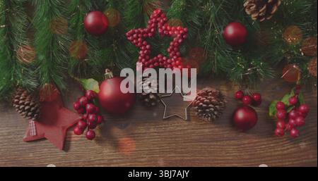 Decorazioni natalizie su un tavolo in legno con baubles rossi, rami di pino e fornelli a stella Foto Stock