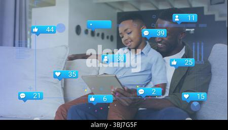Padre e figlio sorridenti che guardano un tablet nel salotto moderno, con icone fluttuanti dei social media Foto Stock