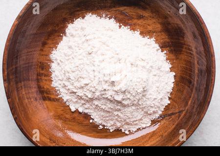Vista dall'alto della farina multiuso in un recipiente, vista dall'alto della farina da forno su un piano di lavoro bianco Foto Stock