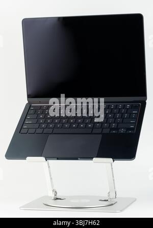 MMinimalistico laptop posizionato su un elegante piedistallo, che ne sottolinea il design elegante e le caratteristiche in un ambiente luminoso. Foto Stock