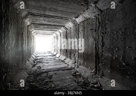 Svuotare il tunnel quadrato di cemento con la luce alla fine Tombini scatolati essiccati. Foto Stock