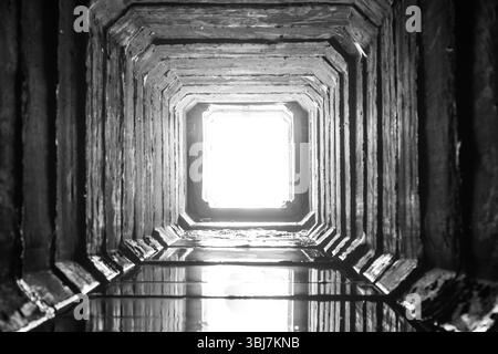 Tunnel di drenaggio quadrato in calcestruzzo con luce alla fine Foto Stock