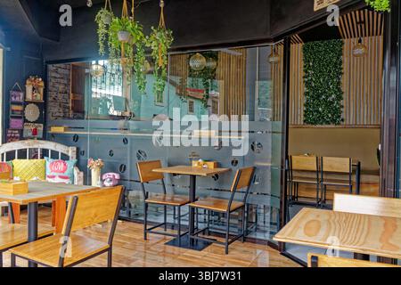 Caffetteria ad angolo con posti a sedere aperta sulla strada e all'interno dietro una parete di vetro a Jinotega, Nicaragua. Semiparete smerigliata con chicchi di caffè in vetro trasparente Foto Stock