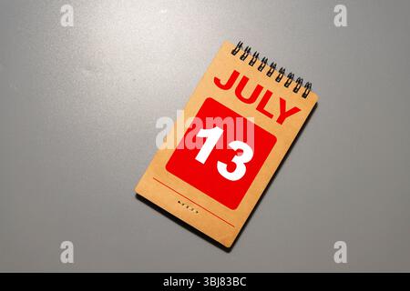 Calendario cubo bianco per luglio decorato con fiori margherita sopra sfondo blu con spazio per la copia Foto Stock